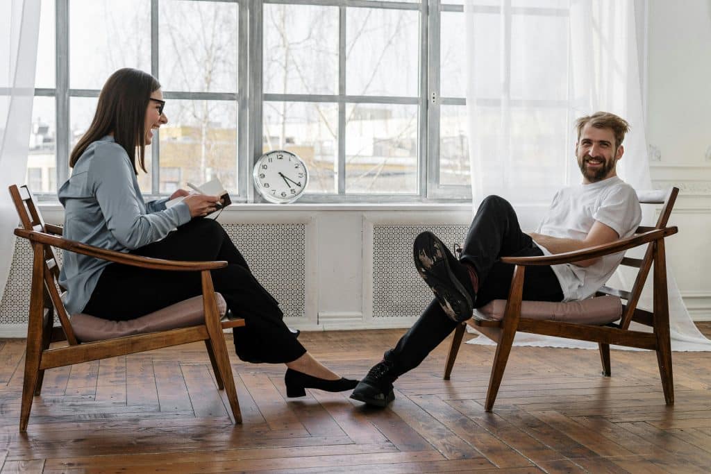Man and woman in a counselling session, with the man smiling, reflecting a positive and supportive therapy environment.