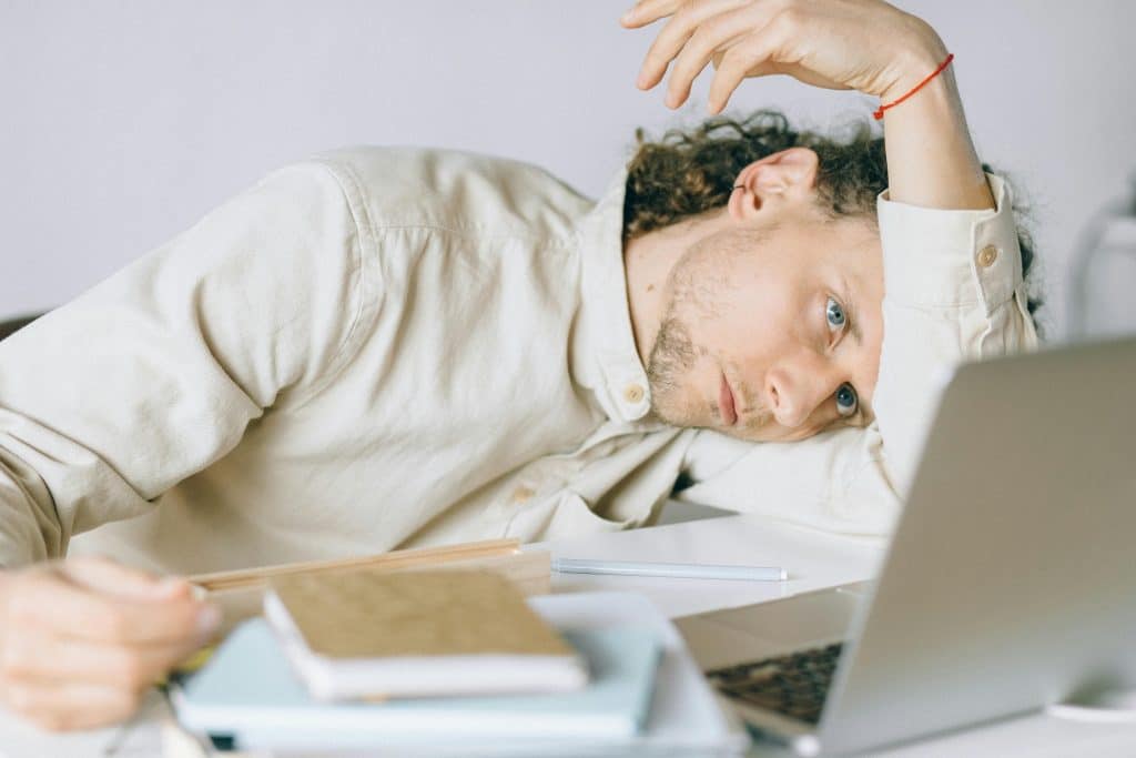 Man at work with laptop looking overwhelmed and burnout